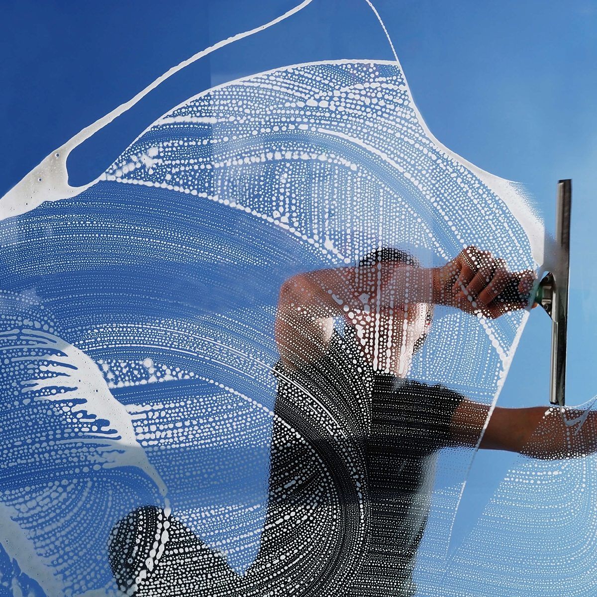 Professional window cleaner squeegeeing a sparkling clean window